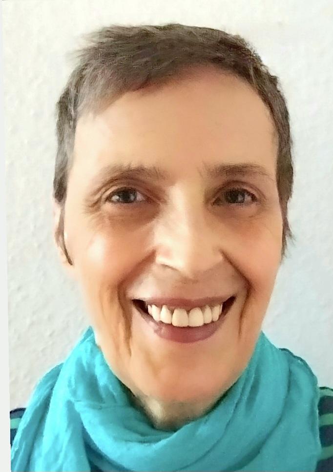 Eine lächelnde Frau mit kurzen Haaren und blauem Schal